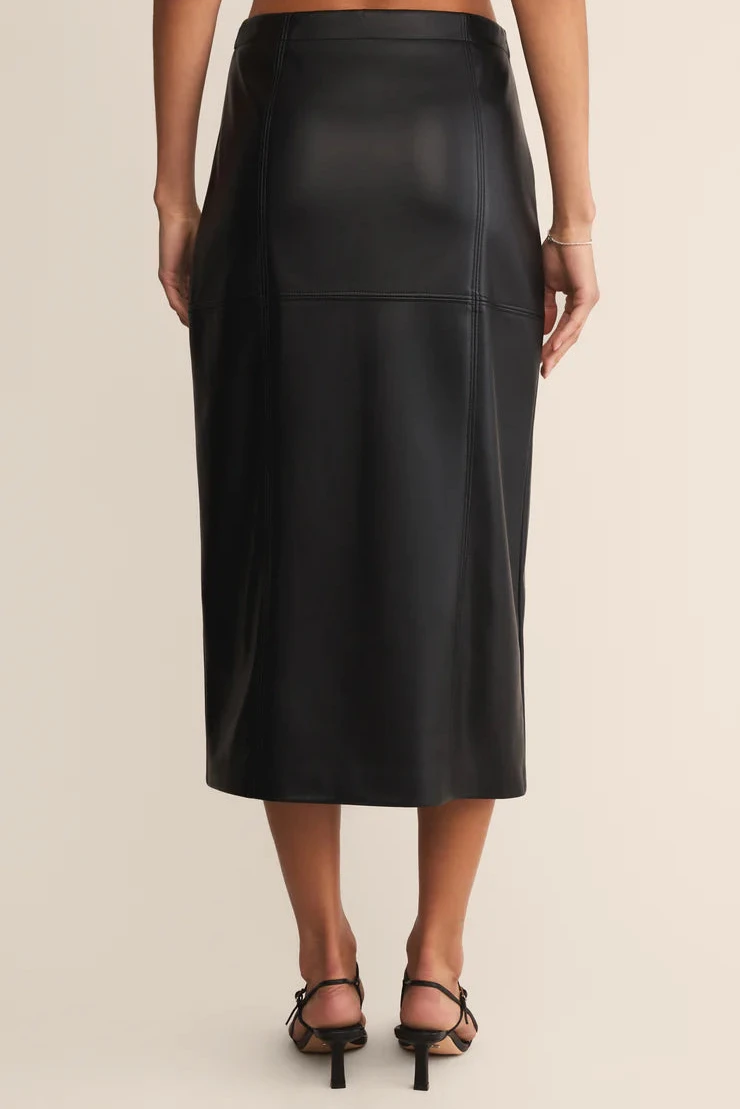 Black leather skirt worn by a person on a beige background