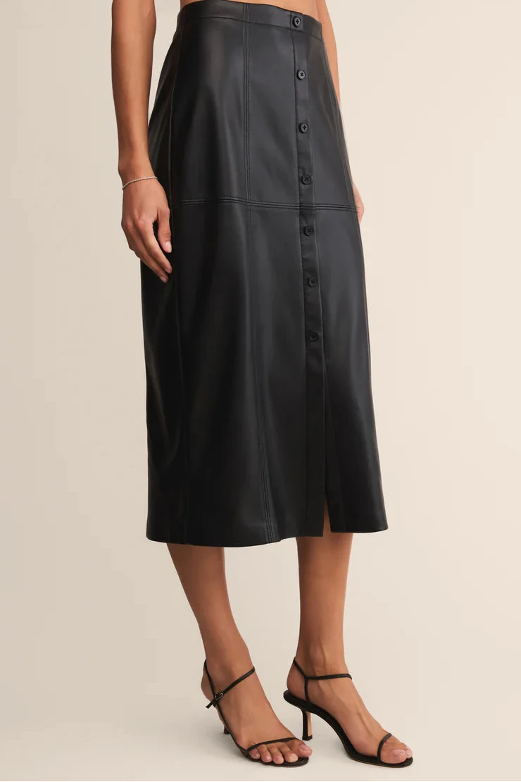 Black leather skirt worn by a person on a beige background