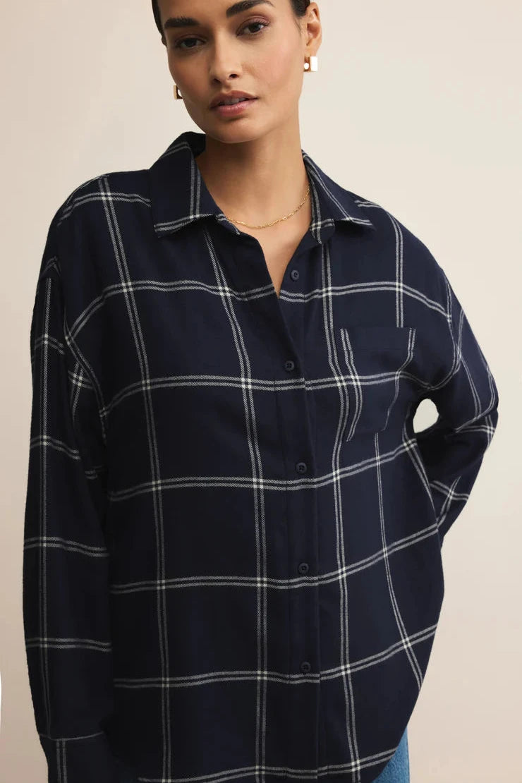 Woman wearing a navy blue plaid shirt against a beige background