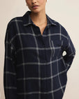 Woman wearing a navy blue plaid shirt against a beige background