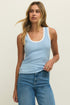 Woman wearing a light blue tank top and blue jeans against a plain background