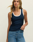 Woman wearing a navy tank top and blue jeans against a plain background