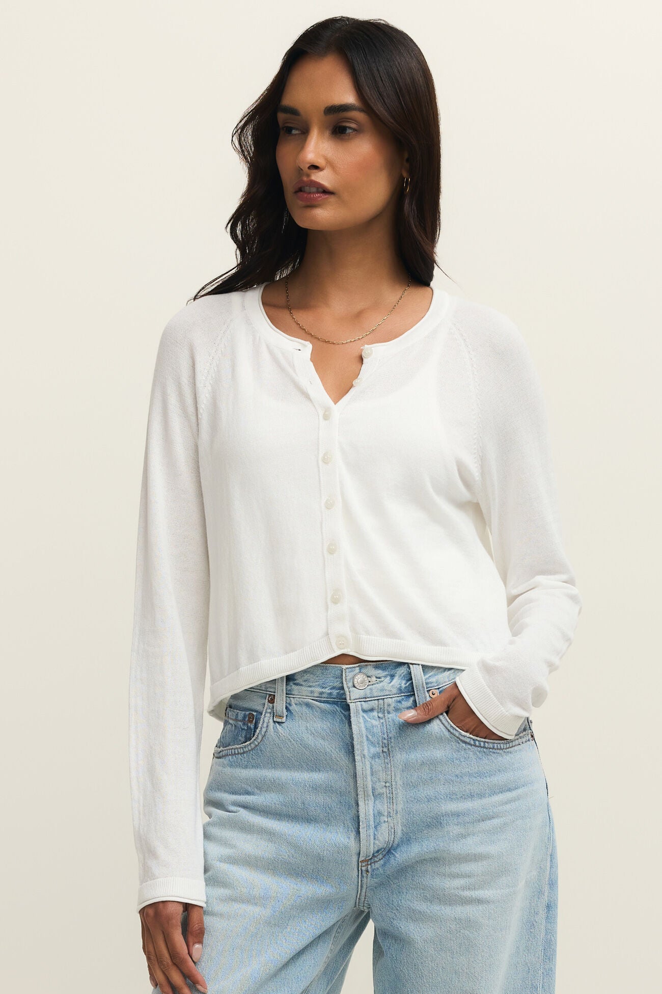Woman wearing a white blouse and light blue jeans against a plain background