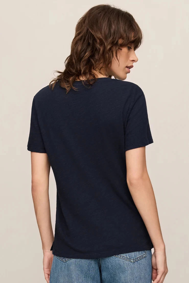 Person wearing a navy blue t-shirt and blue jeans on a beige background