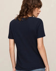 Person wearing a navy blue t-shirt and blue jeans on a beige background