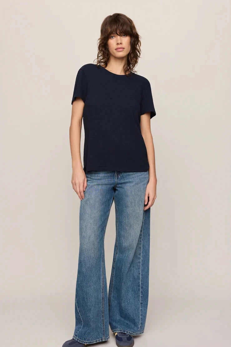 Person wearing a navy t-shirt and blue jeans on a beige background