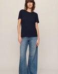 Person wearing a navy t-shirt and blue jeans on a beige background