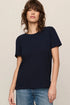 Woman wearing a navy blue t-shirt and blue jeans on a beige background