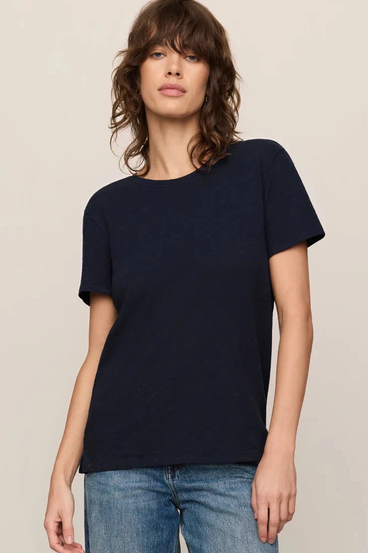 Woman wearing a navy blue t-shirt and blue jeans on a beige background