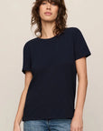 Woman wearing a navy blue t-shirt and blue jeans on a beige background
