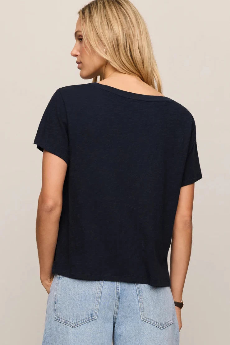 Woman wearing a black t-shirt and light blue jeans on a beige background