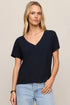 Woman wearing a black V-neck t-shirt and light blue jeans on a beige background