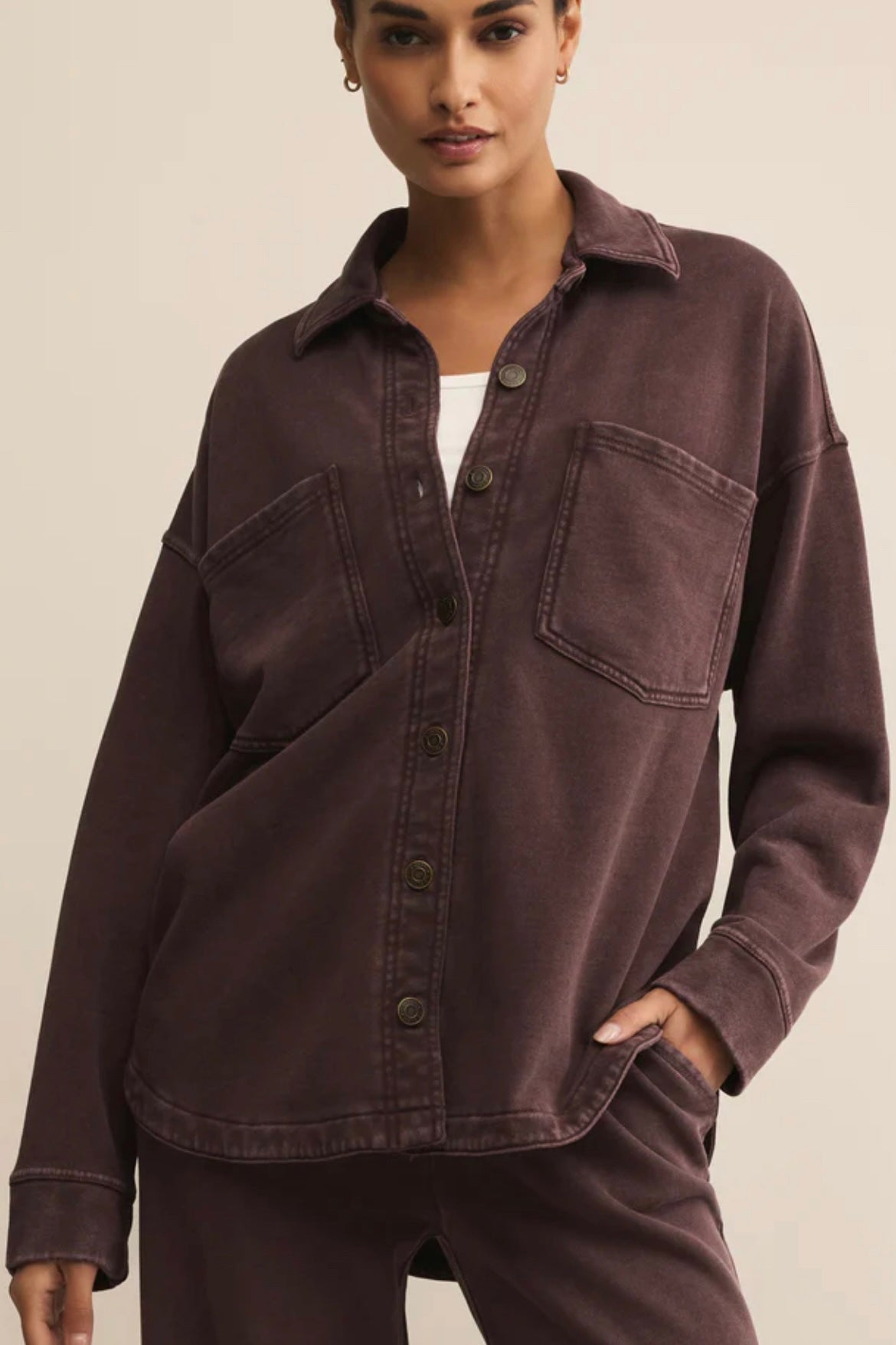 Woman wearing a brown button-up shirt with a neutral background