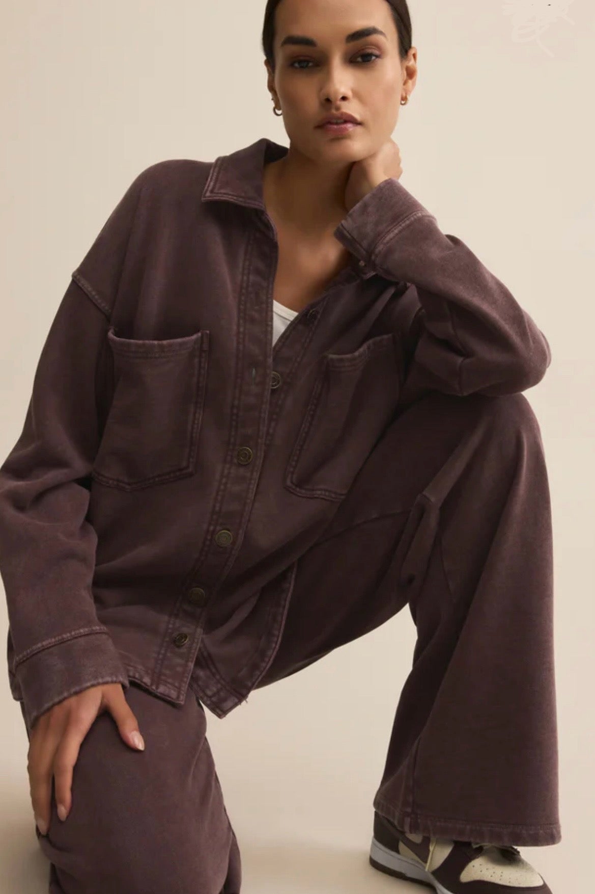 Person wearing a dark brown outfit with a plain background