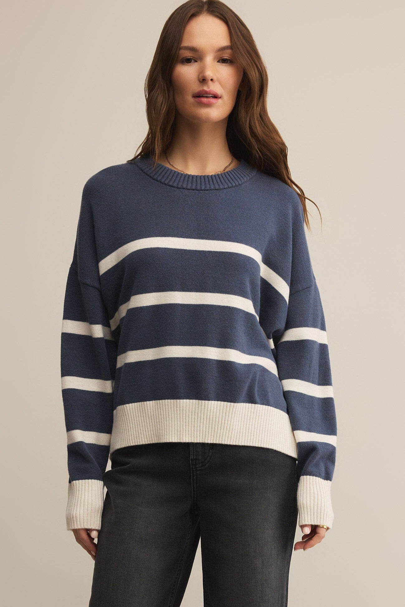Woman wearing a blue and white striped sweater against a beige background