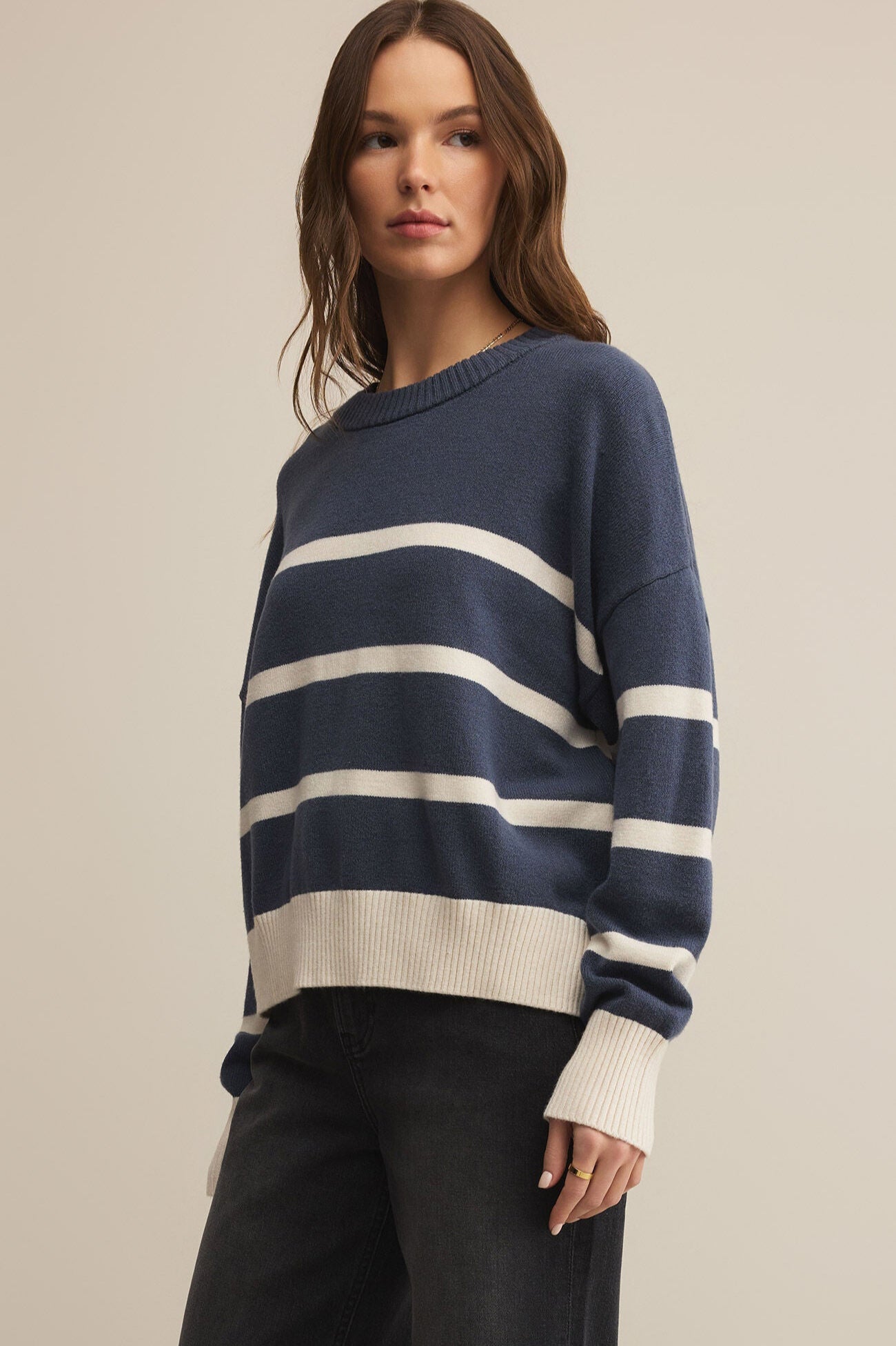 Woman wearing a navy and white striped sweater against a beige background