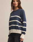 Woman wearing a navy and white striped sweater against a beige background