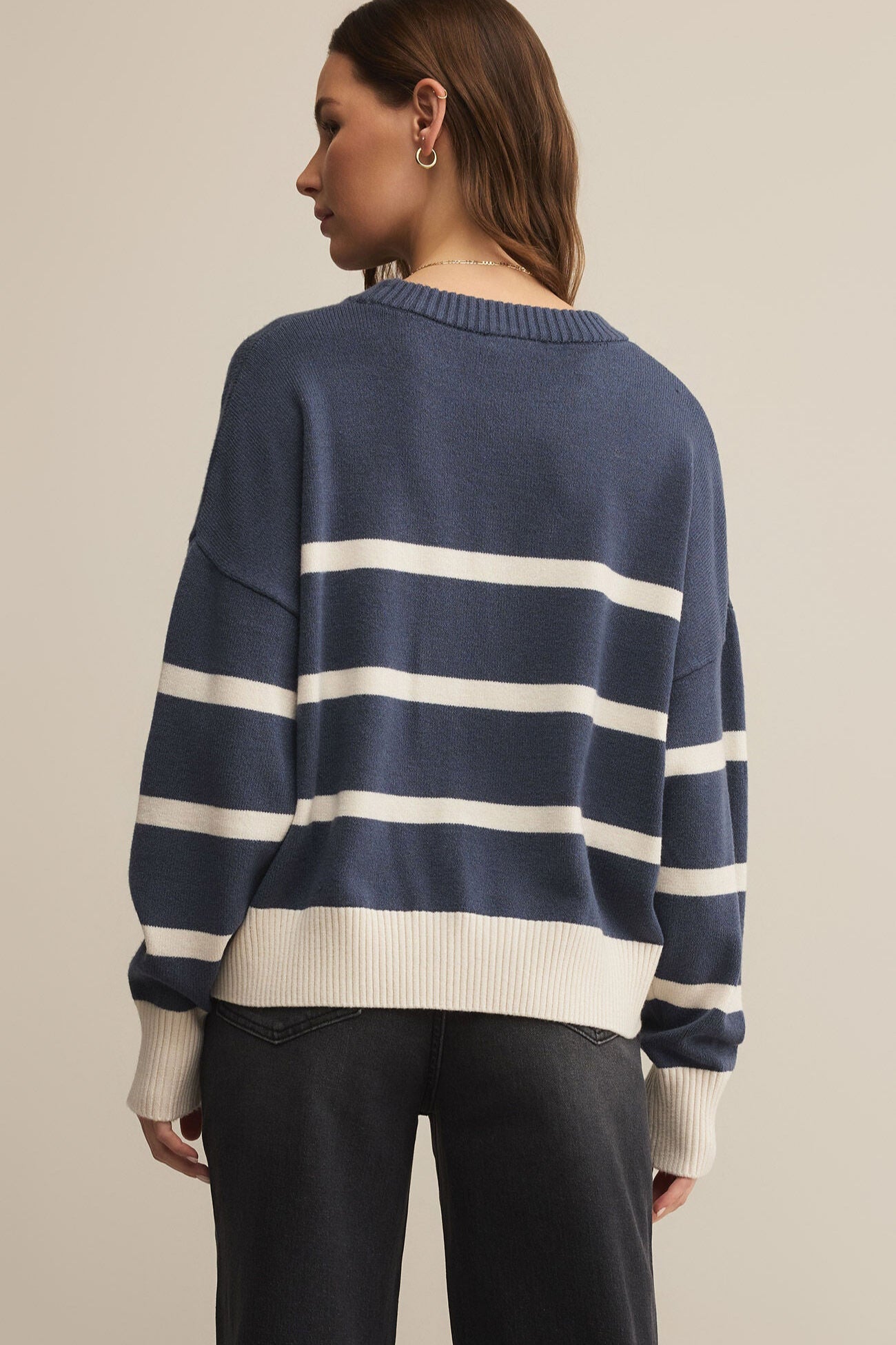 Person wearing a navy and white striped sweater on a beige background