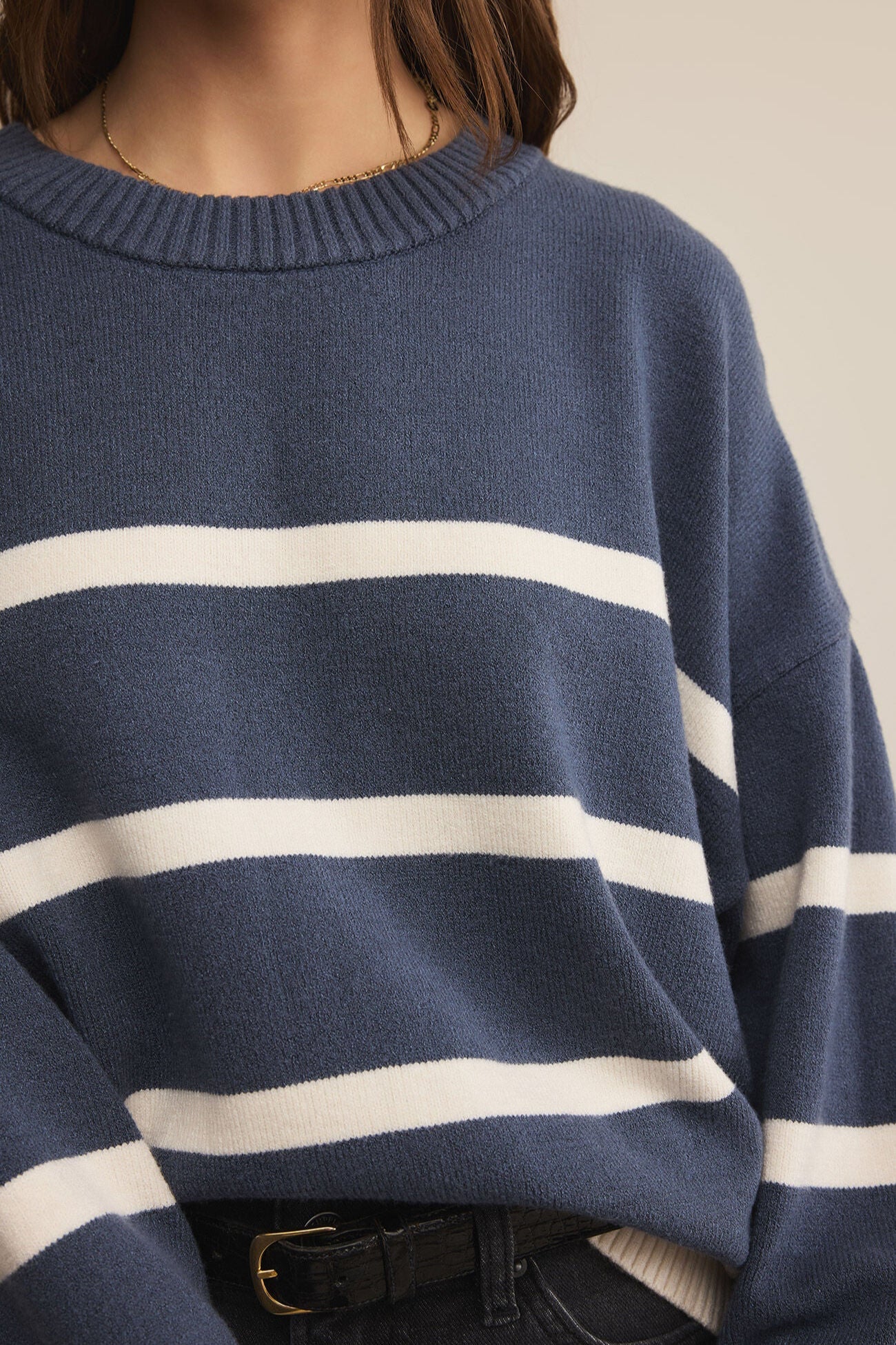 Navy sweater with white stripes worn by a person, on a neutral background
