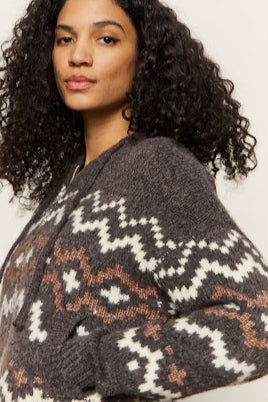 Woman wearing a patterned sweater against a plain background
