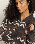 Woman wearing a dark gray sweater with a pattern, against a neutral background