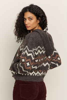 Woman wearing a patterned sweater with a neutral background