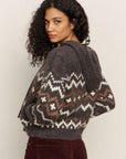 Woman wearing a patterned sweater with a neutral background