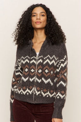 Woman wearing a patterned zip-up sweater against a plain background