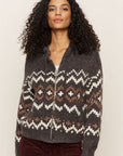 Woman wearing a patterned zip-up sweater against a plain background