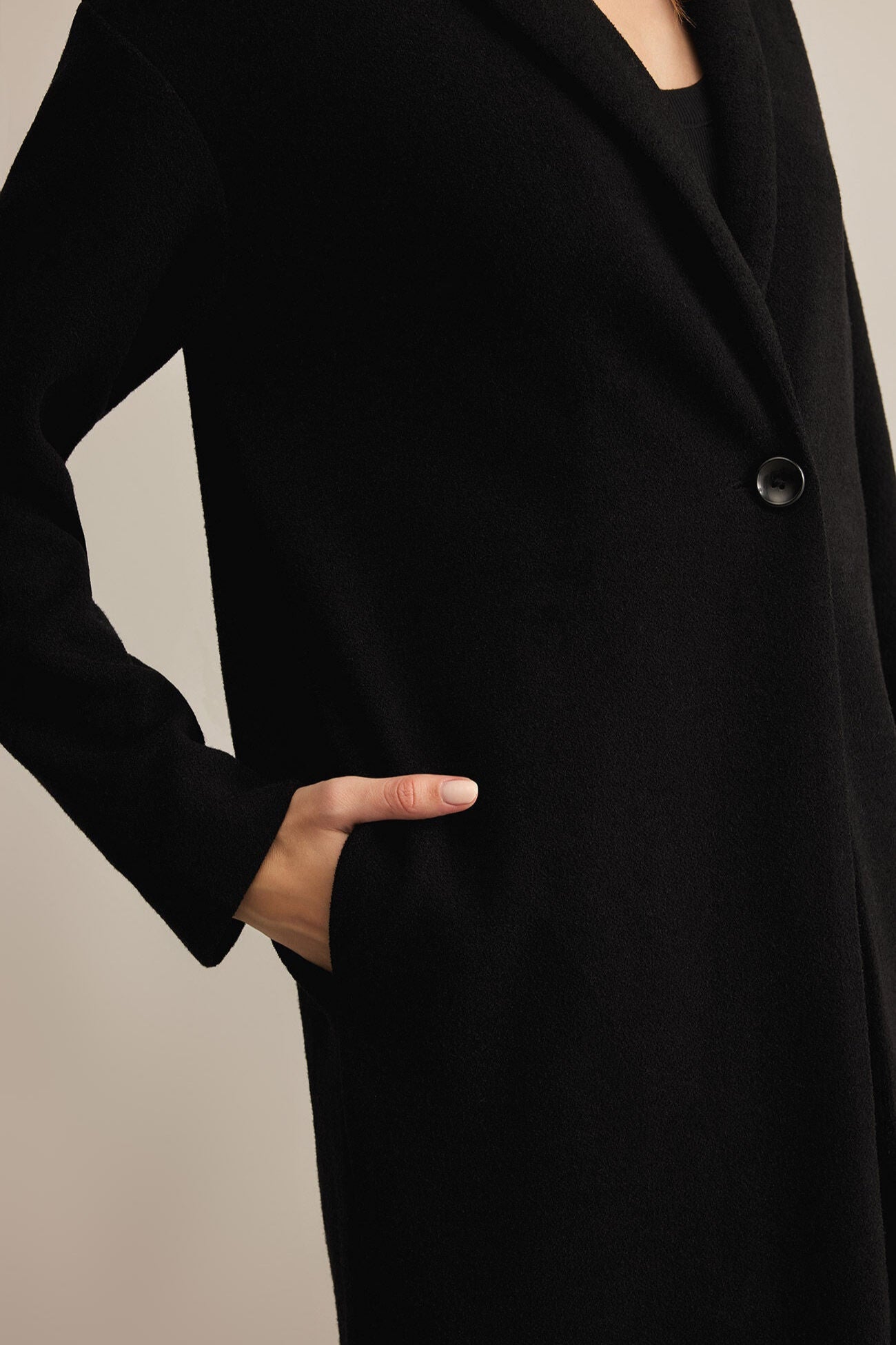 Black coat with a button on a neutral background