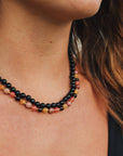 Close-up of a woman wearing a beaded necklace with a blurred natural background
