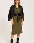 Woman wearing a green dress with a black leather jacket and boots on a white background