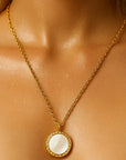 Gold necklace with a round pendant on a person's neck