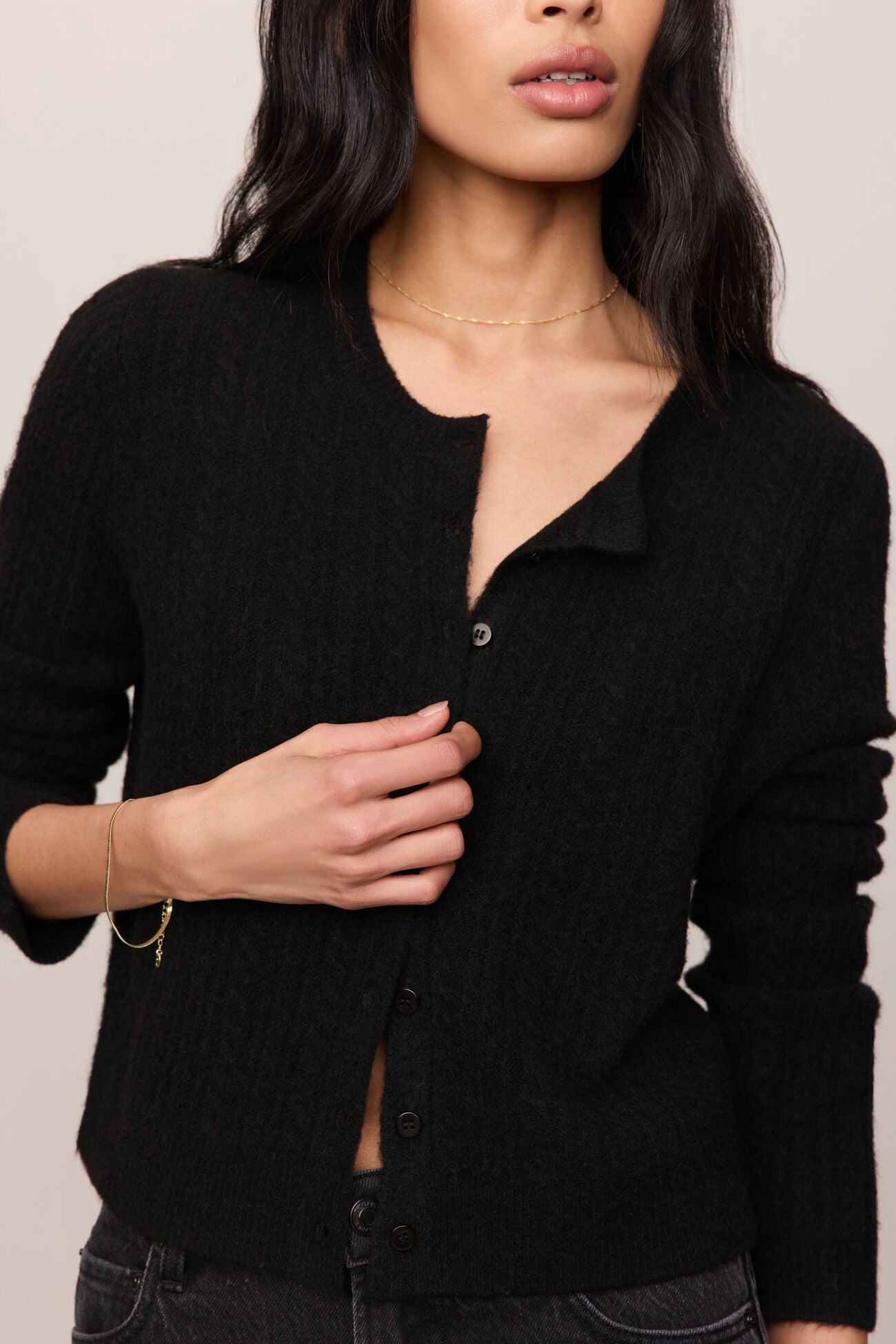 Woman wearing a black cardigan against a neutral background