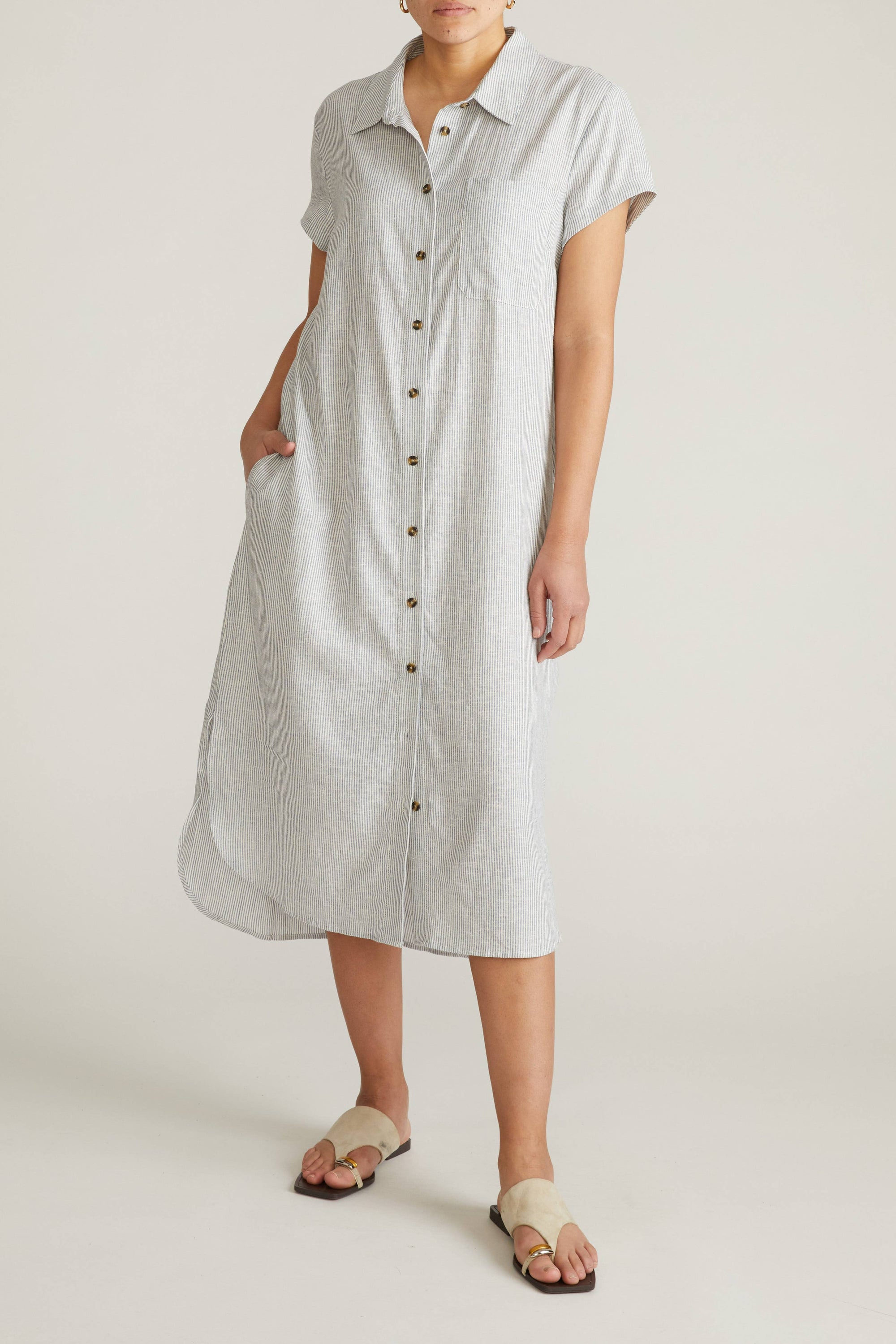 Person wearing a light gray dress with buttons on a white background