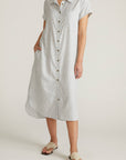 Person wearing a light gray dress with buttons on a white background