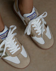 Beige and white sneakers with brand logo on a neutral background