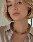Woman wearing a beige shirt and a beaded necklace indoors
