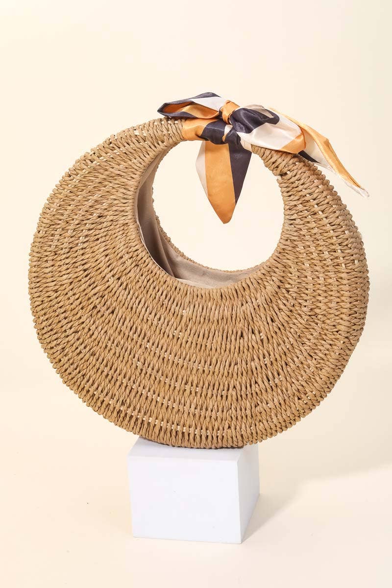 Woven hat with a ribbon on a white stand against a beige background