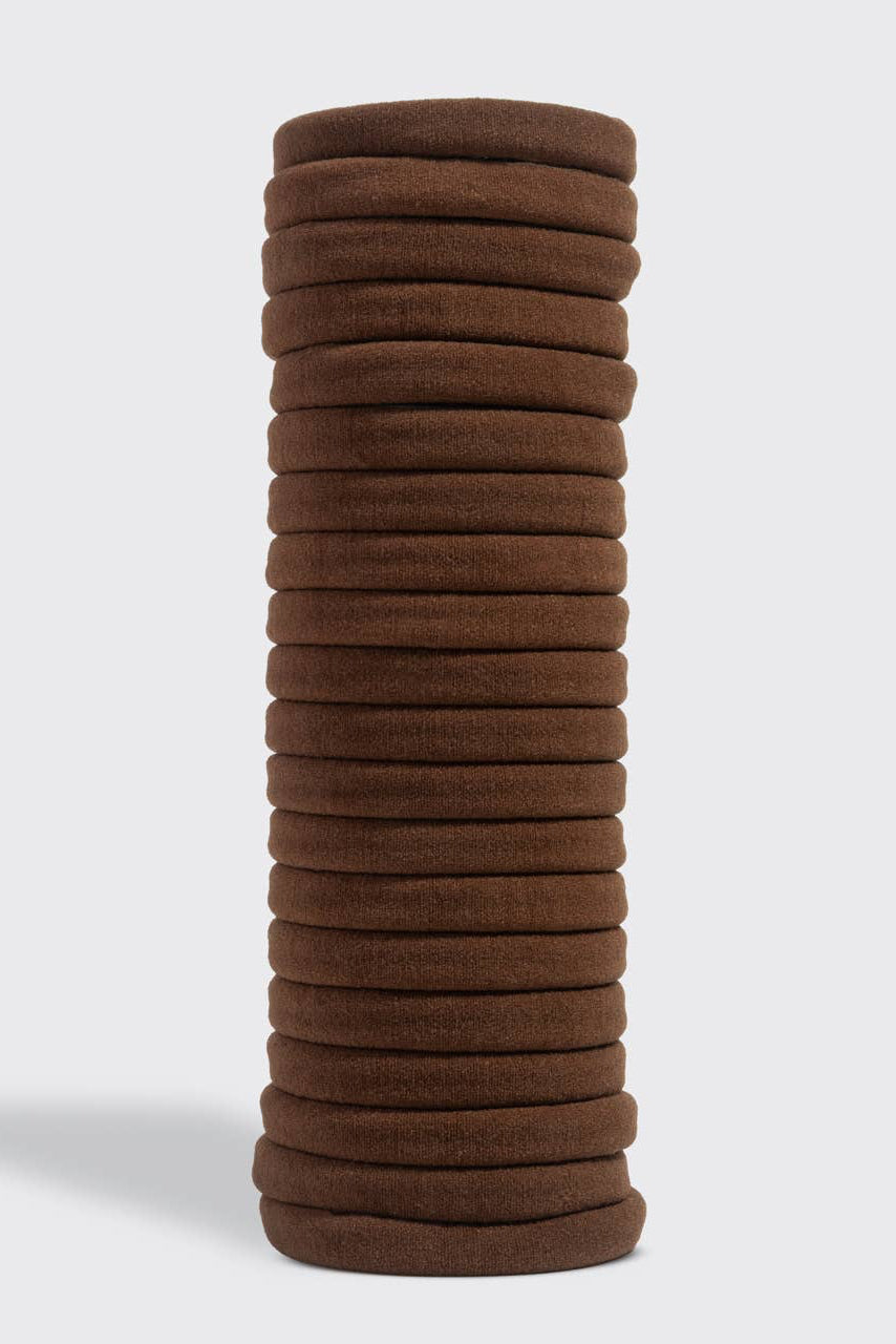 Stack of brown hair ties on a light gray background