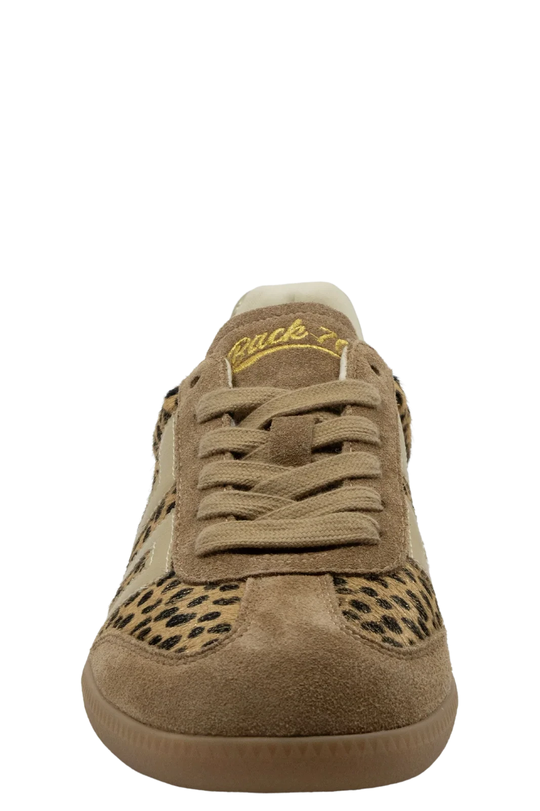 A single low-top sneaker shown from the front on a plain white background. The shoe is primarily tan and brown suede with a leopard print pattern on the toe box and side panels, plus a cream collar and yellow script branding on the tongue.