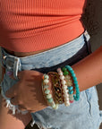 Person wearing multiple bracelets on a wrist with a blurred background