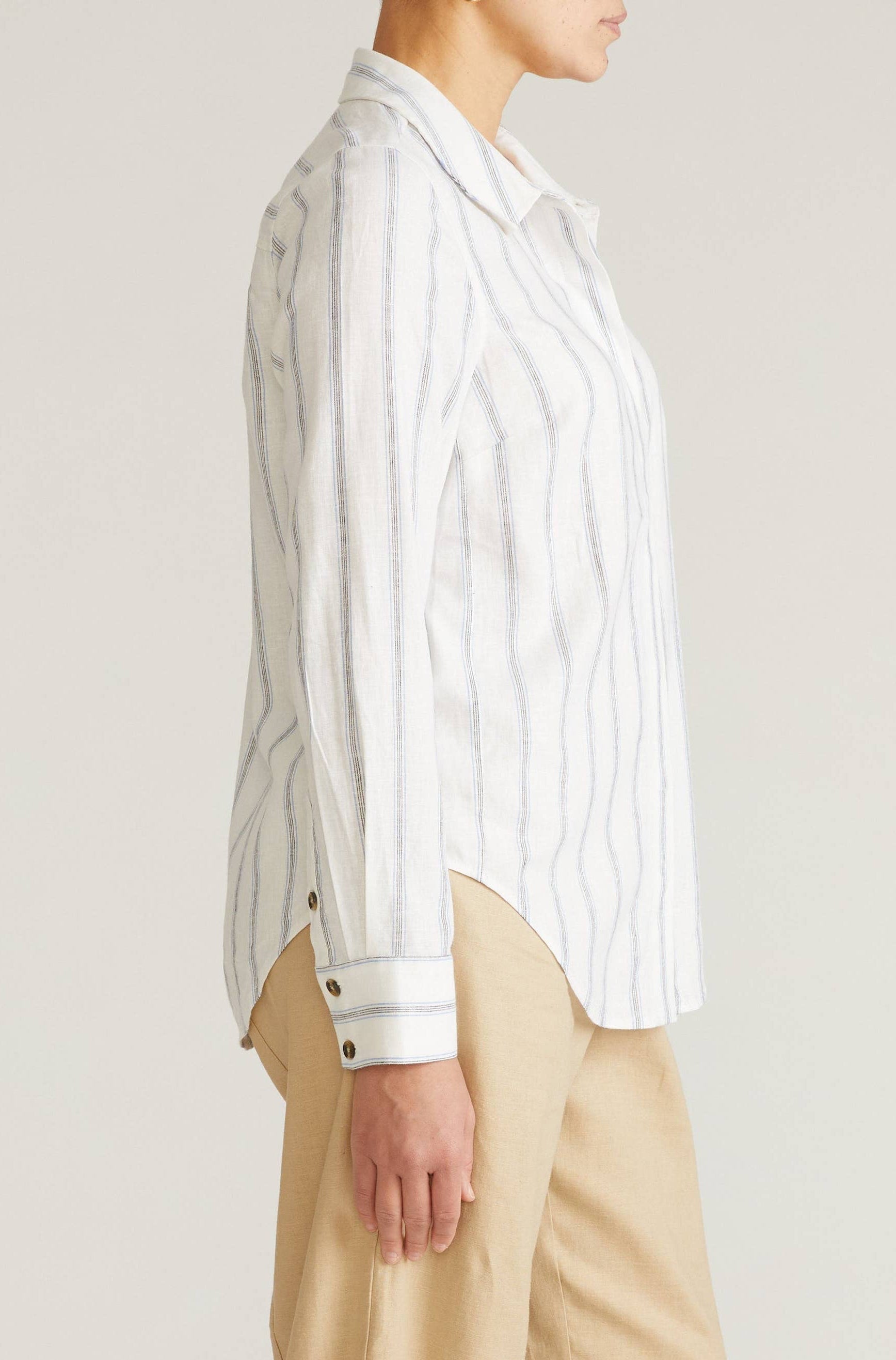 Person wearing a white striped shirt and beige pants on a plain background