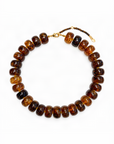 A beaded necklace made of polished amber-brown disc beads with a small gold clasp and extender chain, photographed on a clean white background.
