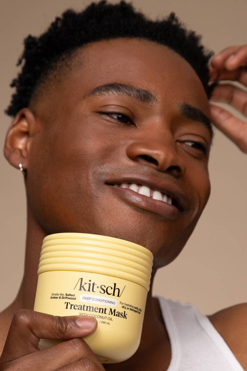 Man holding a jar of 'kit-sch' Treatment Mask against a neutral background