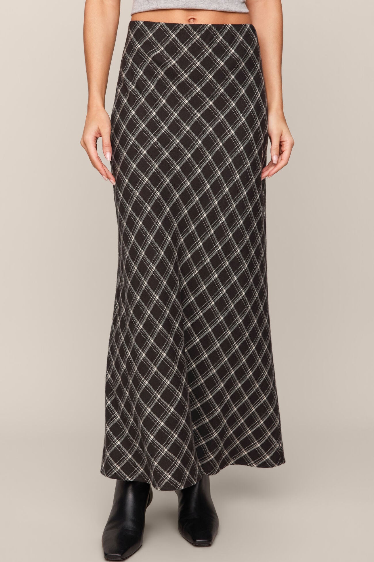 Person wearing a long plaid skirt on a plain background