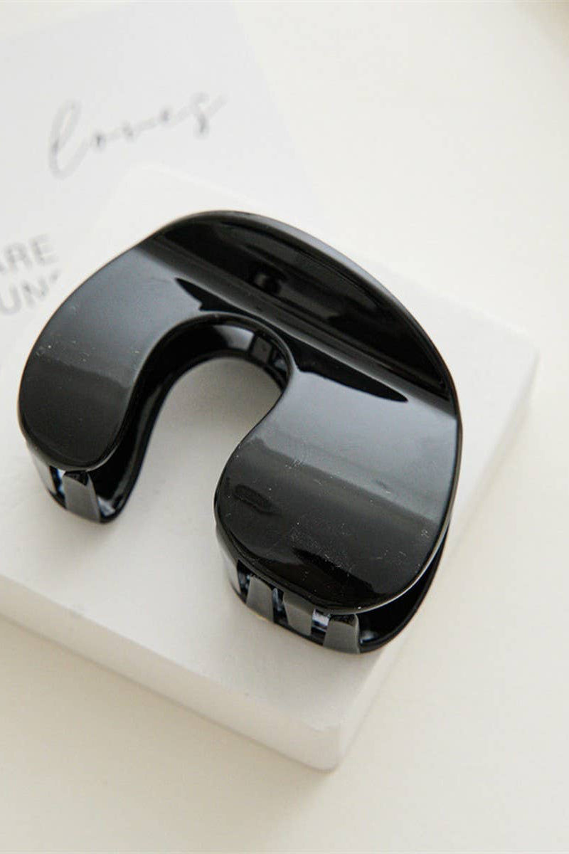 Black neck massager on a white block with a light background