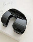 Black neck massager on a white block with a light background