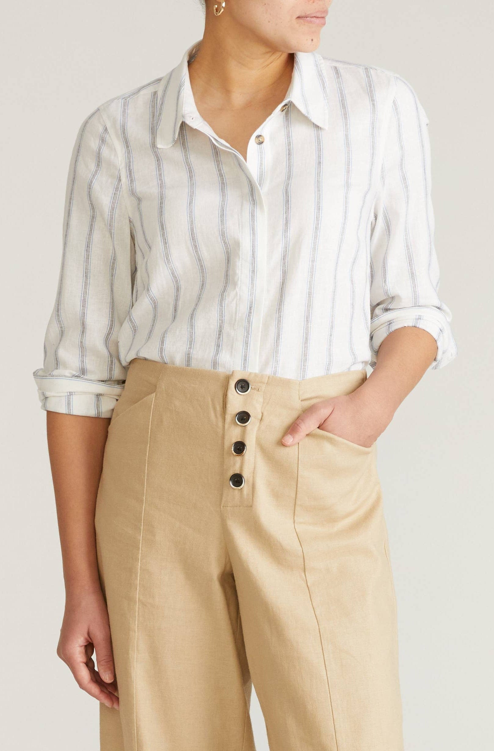 Person wearing a striped shirt and beige pants on a plain background