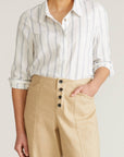 Person wearing a striped shirt and beige pants on a plain background